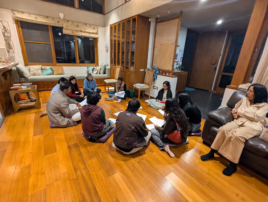The Sanctuary studio on opening night: a circle of people on the wooden floor, warm lamplight